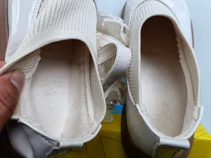 Detail of girls' white patent leather shoes with plush lining and knit sock collar