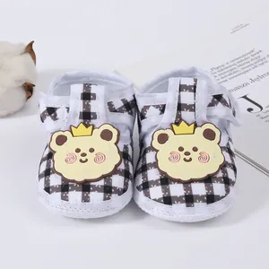 Close-up of baby plaid shoes with cute bear patches and soft cotton flower background