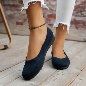 Close-up of navy blue knitted round toe flat shoes worn by a model on wooden floor