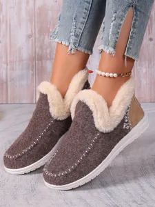 Bottes de neige confortables en daim marron avec doublure en fourrure blanche portées.