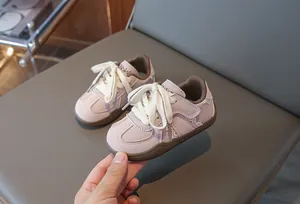Nahaufnahme von schicken rosa Kindersneakern mit braunen Sohlen und weißen Schnürsenkeln