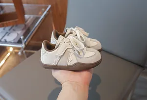 Detailansicht der cremeweißen Kinderschuhe mit Spitzenbesatz und weichen Gummisohlen
