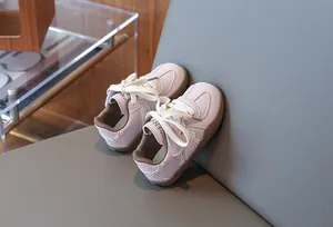 Nahaufnahme von rosa Kinder-Sneakern mit weißen Schnürsenkeln auf einem grauen Stuhl