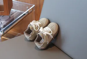 Detailansicht von beigen Kinder-Sneakern mit weicher Sohle auf einem grauen Sessel
