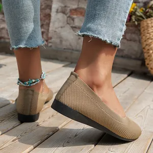 Macro view of breathable khaki knitted flat shoes for women on a sunlit wooden deck
