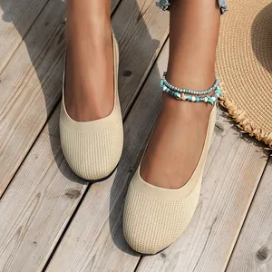Detailed view of women's beige knitted round-toe flat shoes worn on a wooden deck