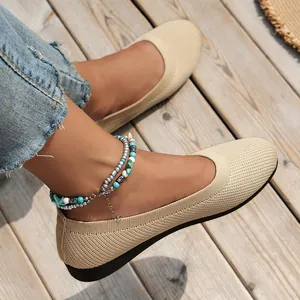 Close-up of stylish beige knitted flat shoes for women shown on a wooden boardwalk