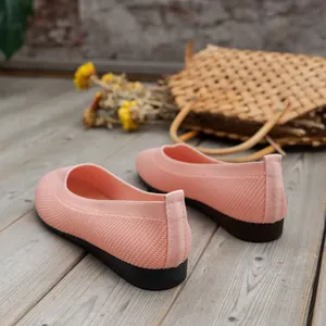 Nahaufnahme von atmungsaktiven rosa gestrickten flachen Damenschuhen auf einem Holzdeck