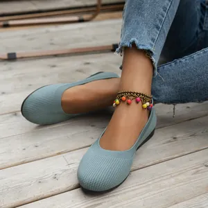 Nahaufnahme von hellblauen, atmungsaktiven Strick-Flachschuhen für Damen auf Holzdeck.