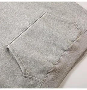 Detailed close-up of a grey hoodie showing the kangaroo pocket and ribbed hem texture.