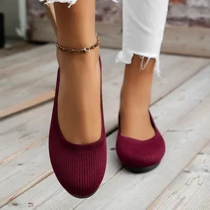 Detailansicht komfortabler weinroter Strickschuhe mit runder Kappe auf Holzboden