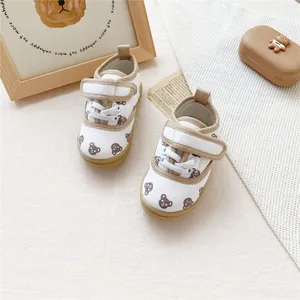 Detail of children's white canvas shoes with brown bear pattern and velcro straps