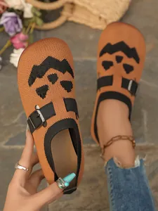 Close-up of orange fly-knit slip-on shoes with a Halloween pumpkin face design.