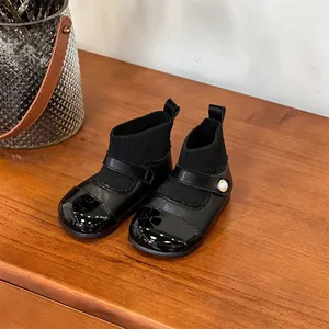 Detailed view of black toddler girl boots featuring a knit sock upper and a pearl strap detail