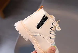 Nahaufnahme weißer Kinderstiefel mit Gänseblümchen-Stickerei und Reißverschluss.