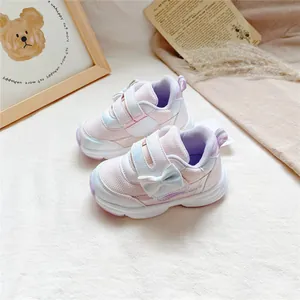 Gros plan de baskets roses pour fillettes avec nœud décoratif et bande velcro