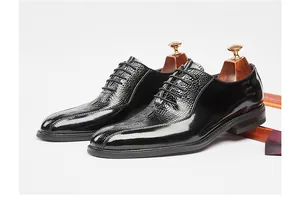Detail view of black leather Oxford dress shoes featuring elegant crocodile embossed patterns