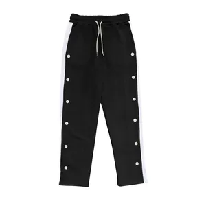 Détail de ce pantalon large noir avec bandes latérales et boutons pressions