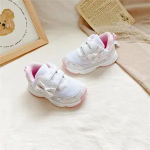Gros plan du nœud rose et du motif cœur sur les baskets respirantes pour filles