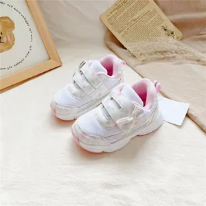 Détail de baskets roses et blanches pour fillettes avec velcro et joli nœud décoratif.