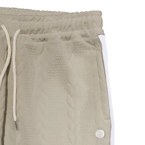 Gros plan du tissu jacquard texturé et de la bande latérale blanche du pantalon homme