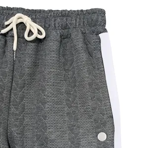 Gros plan d'un pantalon de jogging gris matelassé avec cordon blanc et bande latérale