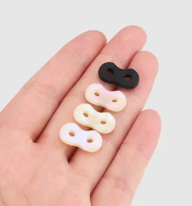 Hand holding four silicone pig nose buckles in black and pearlescent pink for scale.