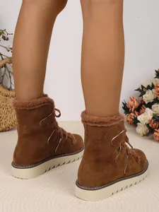 Gros plan de bottes de neige marron en similicuir avec doublure en peluche et semelle épaisse.