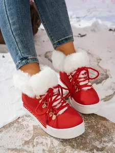 Primer plano de botas de nieve rojas con cordones y forro de piel sintética blanca