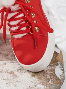 Detalle de botas de nieve rojas para mujer con forro de piel sintética blanca y cordones.