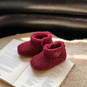 Bottes en peluche rouge pour enfants avec détail cœur sur un livre ouvert