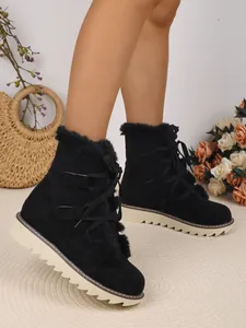 Gros plan de bottes de neige en daim noir avec doublure en fourrure et boucles à lacets