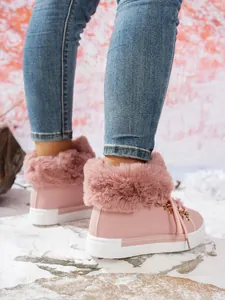 Primer plano de botas de nieve rosa para mujer con cuello de piel sintética y suelas gruesas