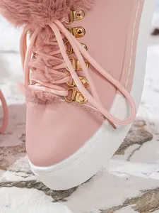 Primer plano de botas de nieve rosas con ribete de piel sintética y ojales de metal dorado