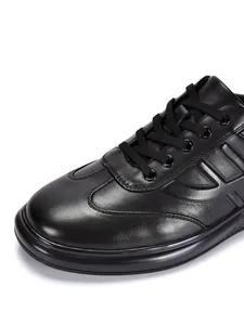 Primer plano de zapatillas de cuero genuino negro con detalles de costura fina