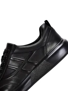 Detalle de cerca de zapatillas casuales para hombre en cuero genuino negro con suela blanda