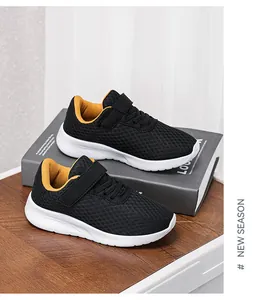 Detalle de zapatillas deportivas de malla negra para niños con forro amarillo y suela blanca.