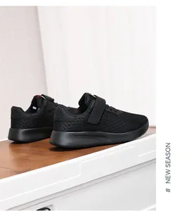 Vista lateral de zapatillas deportivas negras de malla transpirable para niños con velcro.
