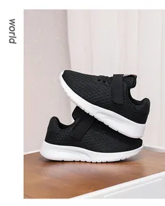 Detalle de cerca de las zapatillas de malla negra para niños con suelas blancas ligeras.