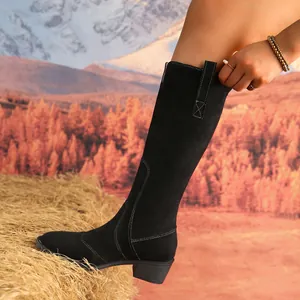 Close-up detail of a stylish black suede knee-high boot featuring a pointed toe and square heel