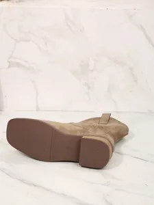 Detail view of the sole and chunky heel of a brown suede Western boot