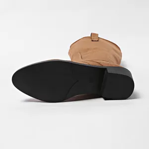 Detailed view of the anti-slip black sole and block heel of tan suede tall boots.