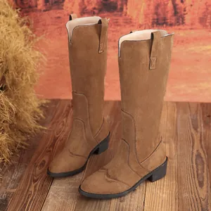 Detailed view of brown suede tall boots with pointed toe and block heel on wooden floor