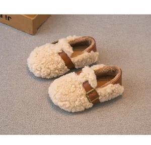 Primer plano de zapatos de lana de cordero para niños con correa de cuero marrón y hebilla