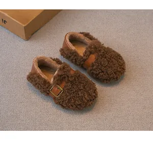 Primer plano de mocasines infantiles de lana de oveja sintética marrón con hebilla