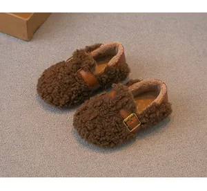Detalle de mocasines infantiles de pelo rizado marrón con forro polar suave y hebilla.
