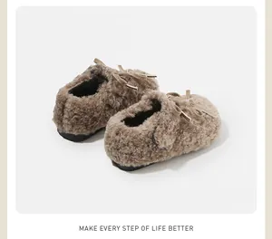 Vista detallada de zapatos de felpa marrón cálido para bebés con un lazo decorativo