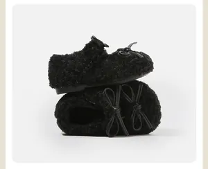 Primer plano de zapatos negros de felpa para bebés con lazos para el calor invernal