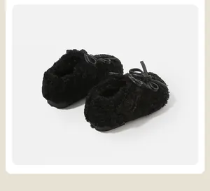 Detalle de zapatos de felpa negra para bebé con suaves lazos decorativos infantiles