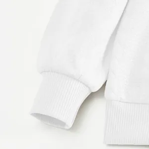 Close-up detail van de geribbelde manchet en jacquardtextuur op een wit zwaar sweatshirt